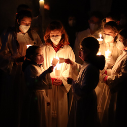 Die Ministranten nehmen das Licht von der Osterkerze und verteilen es.